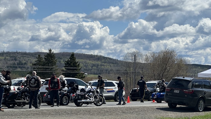 Des motards et des policiers sur une route de campagne.