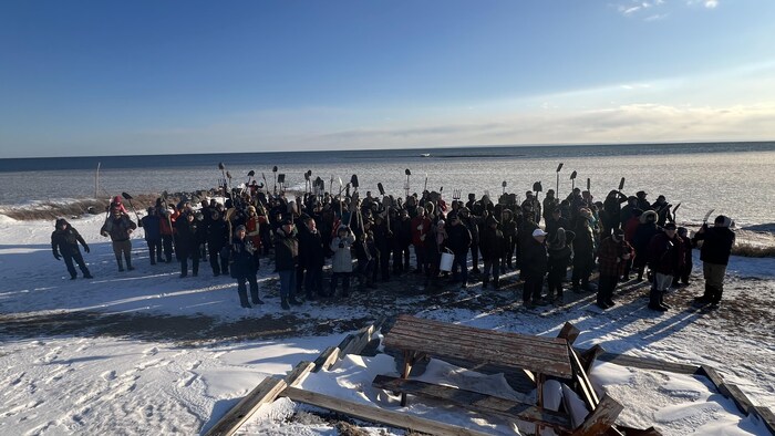 Un groupe de personne sur une plage de Bonaventure tend des pelles et des perches.