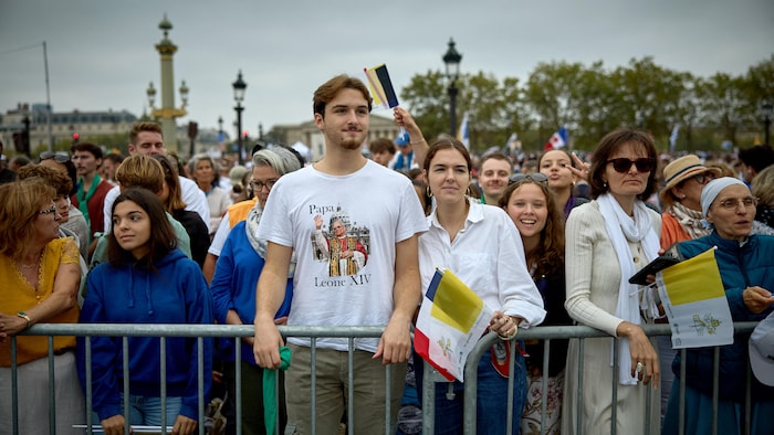 Des gens se rassemblent sur les Champs-Élysées derrière une barrière de sécurité.
