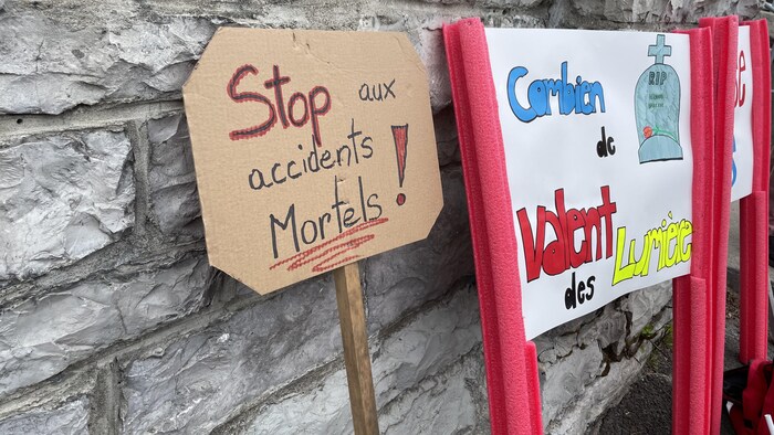 Des affiches posées sur un mur de pierres d'une église.