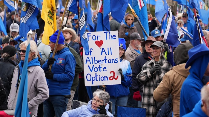 Un groupe de gens habillés en bleu avec des drapeaux albertains.