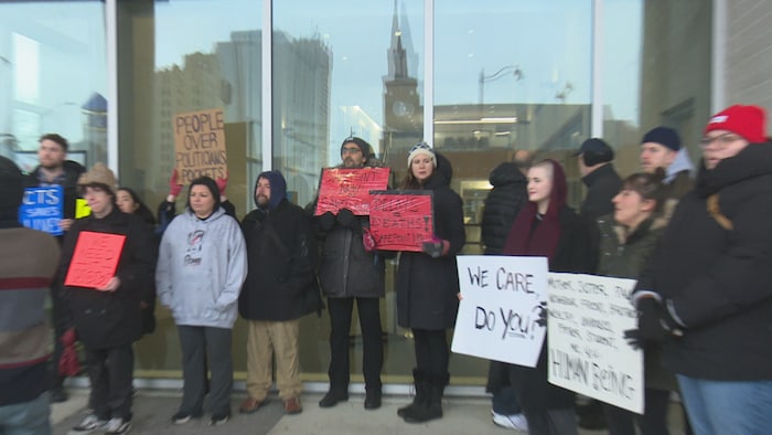 Des membres du public portent des pancartes avec des messages de soutien au centre de consommation et de traitement.
