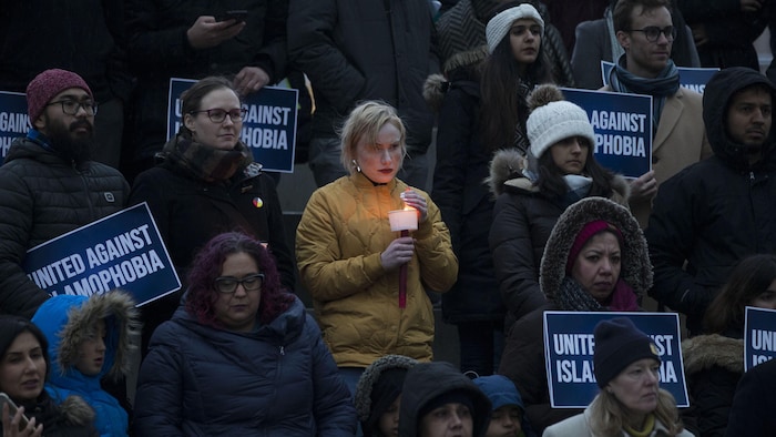 Des gens tiennent une bougie ou une affiche sur laquelle on peut lire : « Unis contre l'islamophobie ».