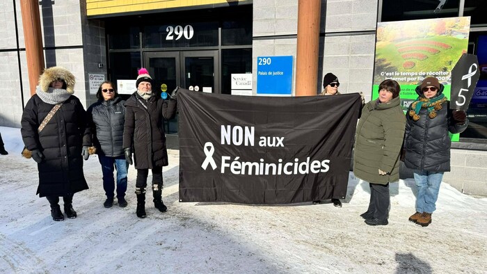 Des femmes tiennent une bannière dénonçant les féminicides.