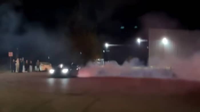 Une voiture en marche qui boucane avec des feux d'artifice au-dessus. 