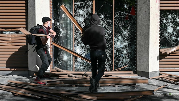 Des manifestants endommagent un bâtiment.