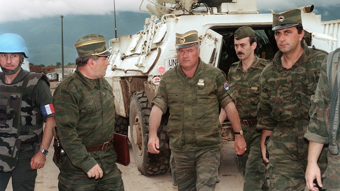 Des militaires serbes et un Casque bleu français marchent.