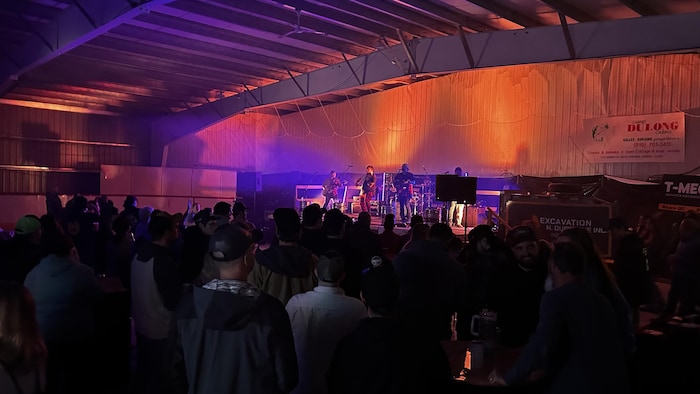 Dans une salle, un groupe performe sur une scène devant une foule.