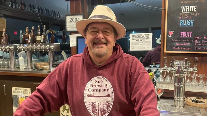 Portrait de Ray Bauer debout derrière le comptoir de sa brasserie.