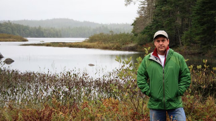 Ray Plourde devant un lac dans une forêt.