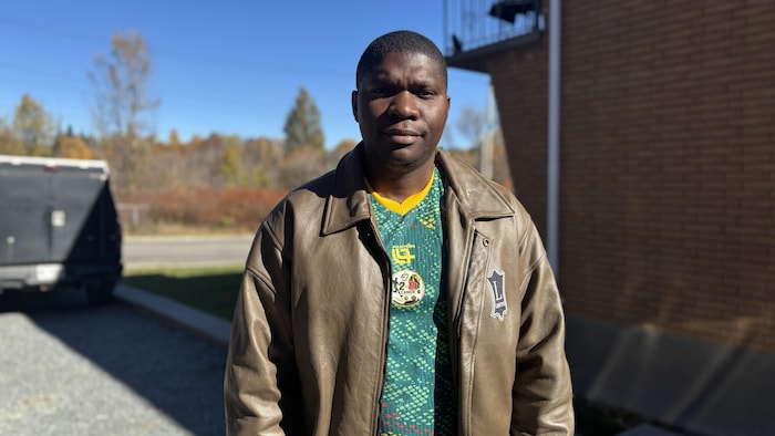 Portrait de Raymond Lionel Ndoumba dans un stationnement.