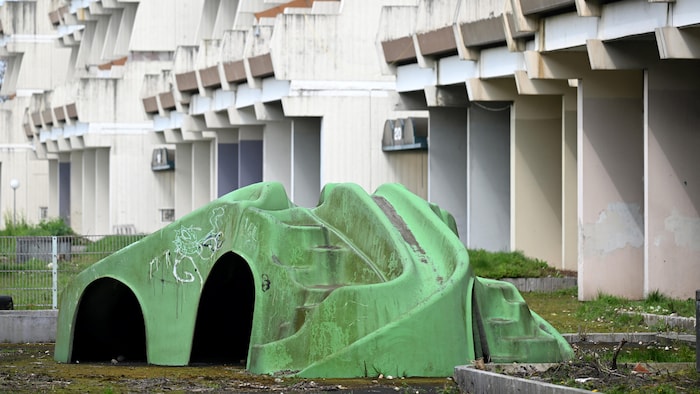 Un module de jeu vert pour enfants est couvert de graffitis et de détritus.