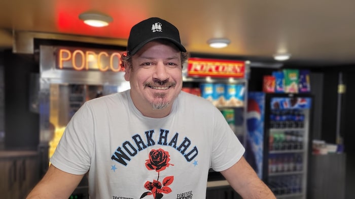Jimmy Larouche sourit devant une machine à popcorn.