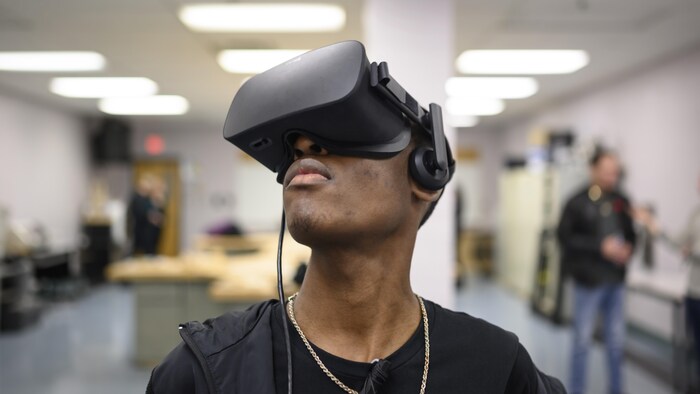 Un adolescent avec un casque de réalité virtuelle qui lui couvre les yeux.
