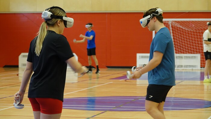 Des étudiants dans un cour d'éducation physique, dans un gymnase, portent des casques de réalité virtuelle.