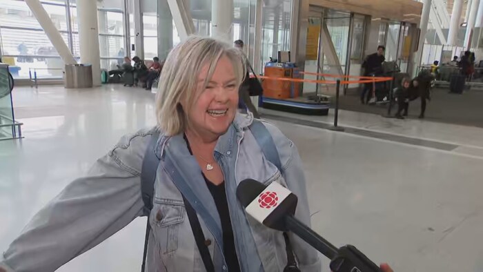 Une femme sourit en parlant à une journaliste.