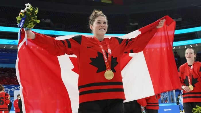 Rebecca Johnston avec une médaille d'or autour du coup et un chandail de Hockey Canada. 