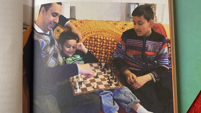Photo tirée d'un livre où on aperçoit un père avec ses deux enfants sur un sofa. 