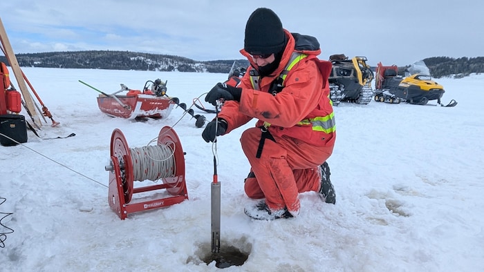 M. Roy retire un tube cylindrique d'un trou dans la glace.