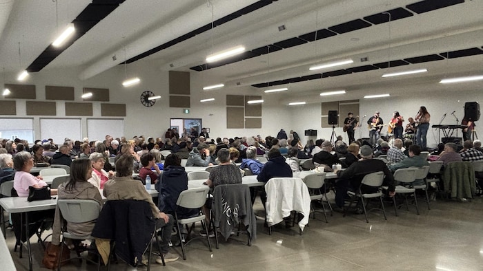 Plusieurs personnes assises dans une salle communautaire.