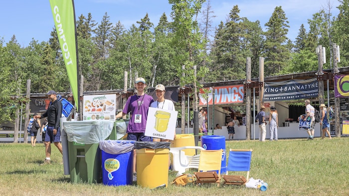 Deux personnes autour de bacs à déchets le 13 juillet 2024 à Winnipeg.