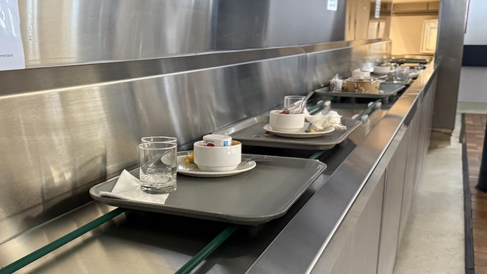 Des cabarets avec des restants de tables sont alignés sur un convoyeur.