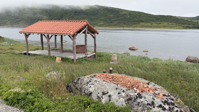 Des morceaux de tuiles orangées éparpillés sur l'île, avec une structure en bois au toit orangé en arrière-plan.