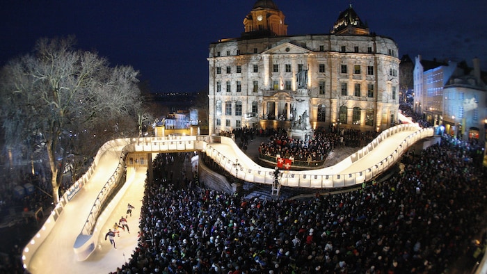 Une piste glacée dans un Vieux-Québec rempli de spectateurs, la nuit.