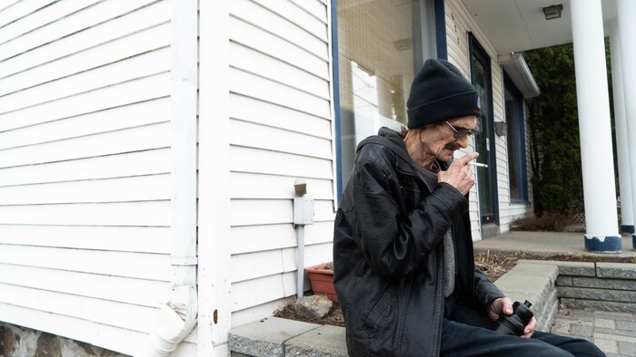 Un homme fume une cigarette à l'extérieur d'un établissement.