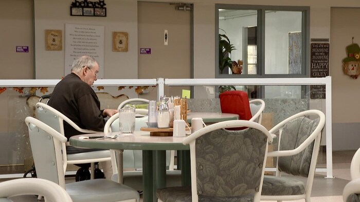 Un homme âgé est assis seul à une table.