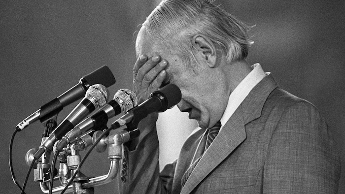 Archive photo of René Lésveque holding his head in front of microphones.