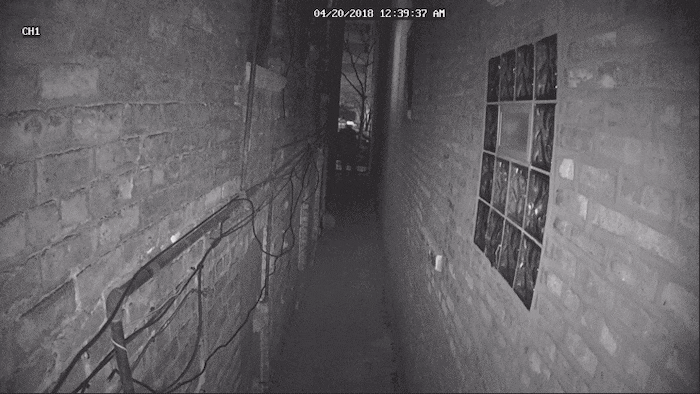 Un homme marche dans une allée sombre. Son visage est recouvert d'une lueur blanche.