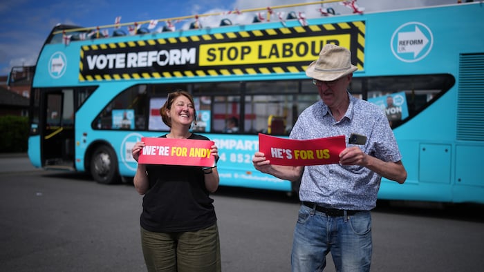Des partisans d'Andy Burnham devant l'autobus de campagne de Reform UK.