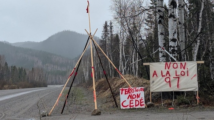 un tipi en bois et des pancartes en bordure d'une route