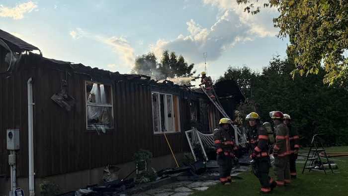Des pompiers autour d'une maison incendiée.