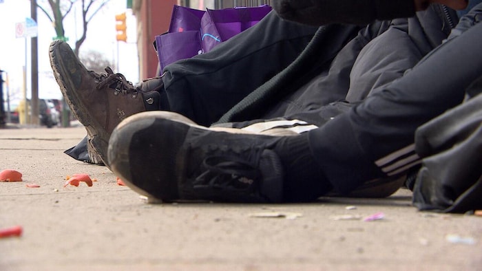 Les pieds de deux itinérants, assis à l'extérieur du centre d'injection supervisés Prairie Harm Reduction à Saskatoon.