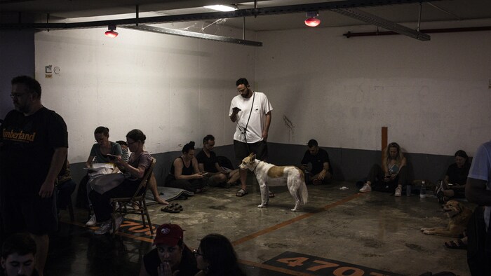 Des personnes attendent dans un stationnement souterrain.