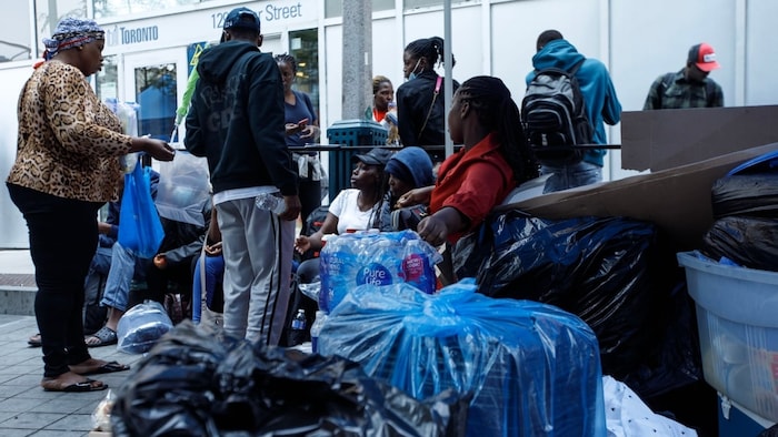 Asylum seekers from Africa and elsewhere wait with their belongings outside a Toronto shelter office in July 2023. A lack of shelter space in the city forced many to sleep outside.