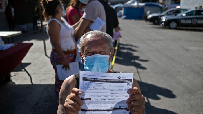 Guatemalan migrant Nery Roberto Espana, who is camping at El Chaparral crossing port, shows his vaccination registry before being vaccinated against COVID-19 alongside asylum seekers and other migrants in Tijuana, Baja California state, Mexico, on the border with the US, on August 3, 2021. - Despite US authorities stating that asylum seekers camping at the border will not receive any special treatment, hundreds of asylum seekers remain at El Chaparral in hope of a policy change.