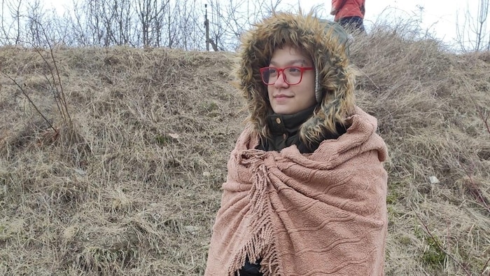 Une femme portant un manteau d'hiver regarde au loin.