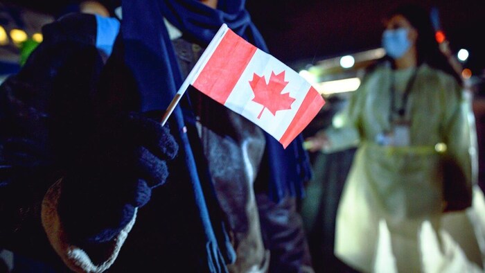 An Afghan refugee holds a small Canadian flag at the St. John's International Airport on Oct. 26, 2021.