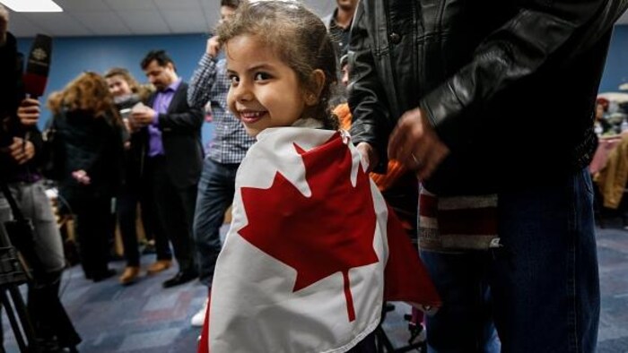 طفلة سورية لاجئة تلتف بالعلم الكندي.