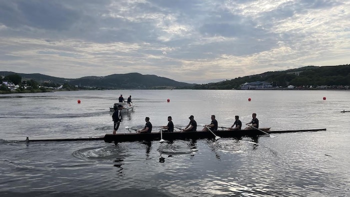 Une équipe d'aviron sur un lac à l'aube.
