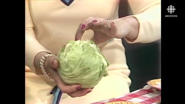 Une pomme de laitue iceberg dans les mains d'une femme.