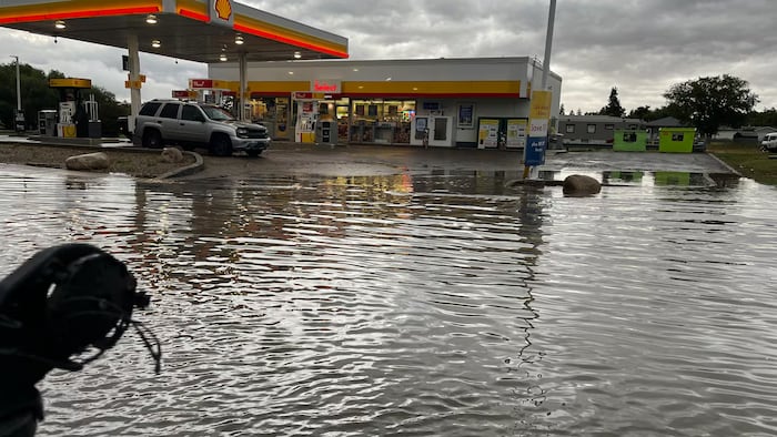 Une route inondée devant une station d'essence.