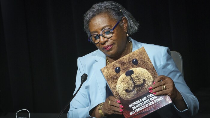 Régine Laurent, assise pour un point de presse, tient son rapport.