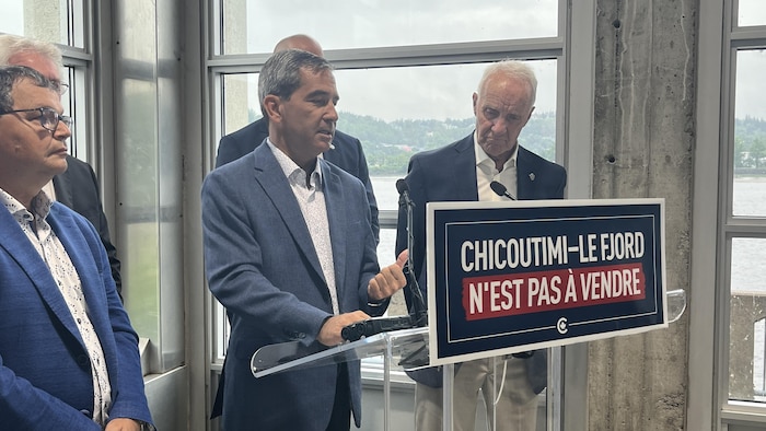 Pierre Paul-Hus parle derrière un lutrin entouré d'autres politiciens.