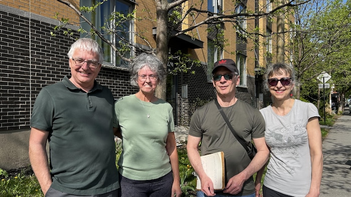 Quatre personnes devant un édifice.