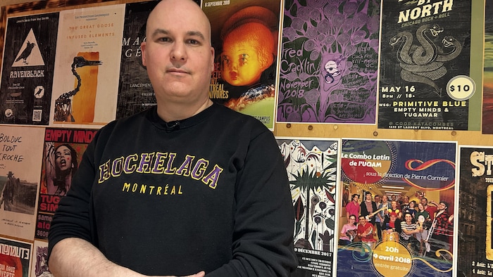 Le gérant des studios de musique devant des affiches musicales. 