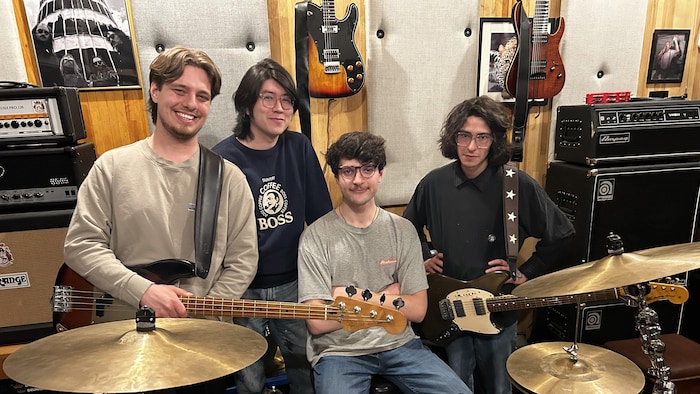 Quatre jeunes musiciens derrière une batterie.